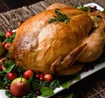 Golden brown, roast turkey garnished with pears, crab apples, cranberries, savory and kale.
